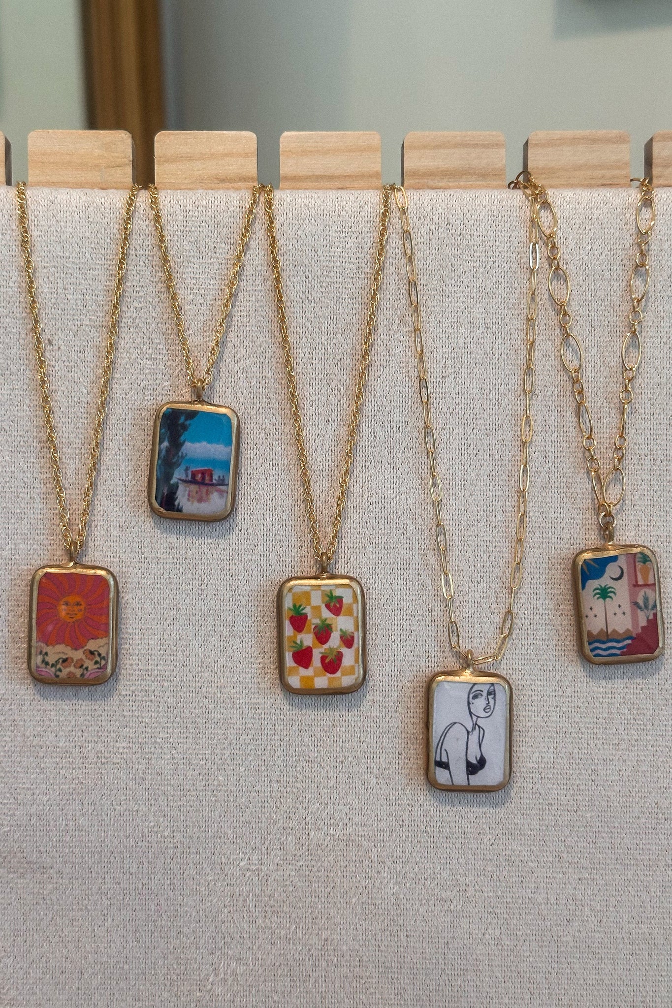 Five necklaces with unique pendants on a gray surface