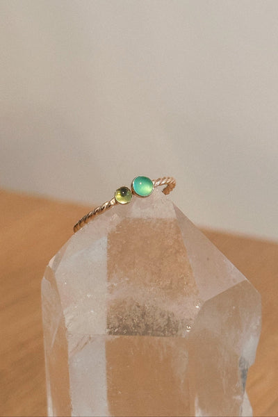 Gold ring with green gemstones on a clear crystal prism