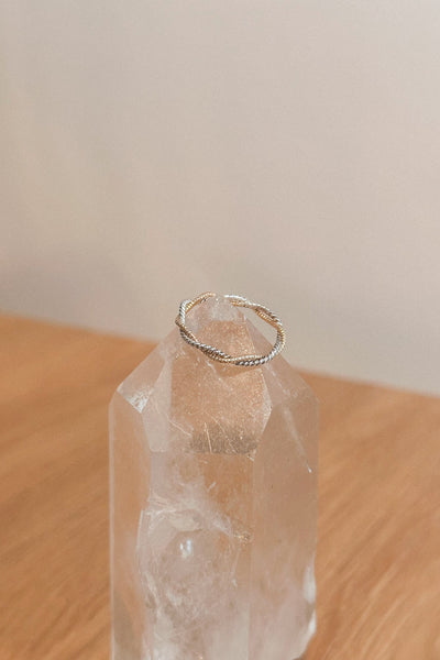Gold ring on a clear crystal on a wooden surface with a neutral background