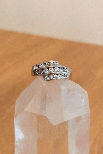 Silver ring with embedded stones on a clear crystal with a wooden surface background