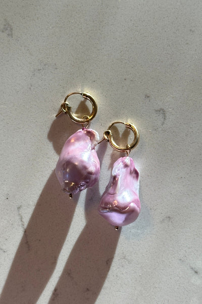 lavender purple baroque pearls with gold hoops on a light gray surface