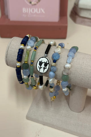 Stack of beaded bracelets on a gray cushion with a blurred background