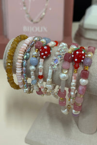 Stack of colorful beaded bracelets on a mannequin arm with a blurred background