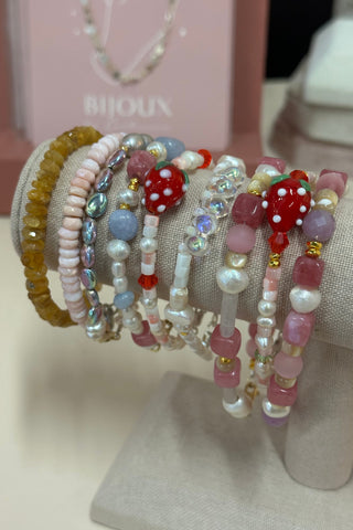 Stack of colorful beaded bracelets on a mannequin arm with a blurred background
