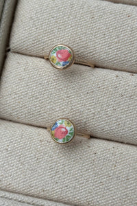 Two floral rings on a textured beige surface