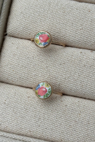 Two floral rings on a textured beige surface