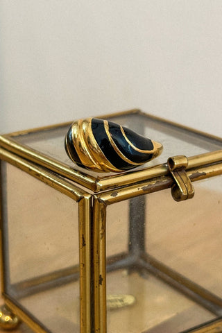 Gold and black spiral vintage ring on a glass display box with gold frame