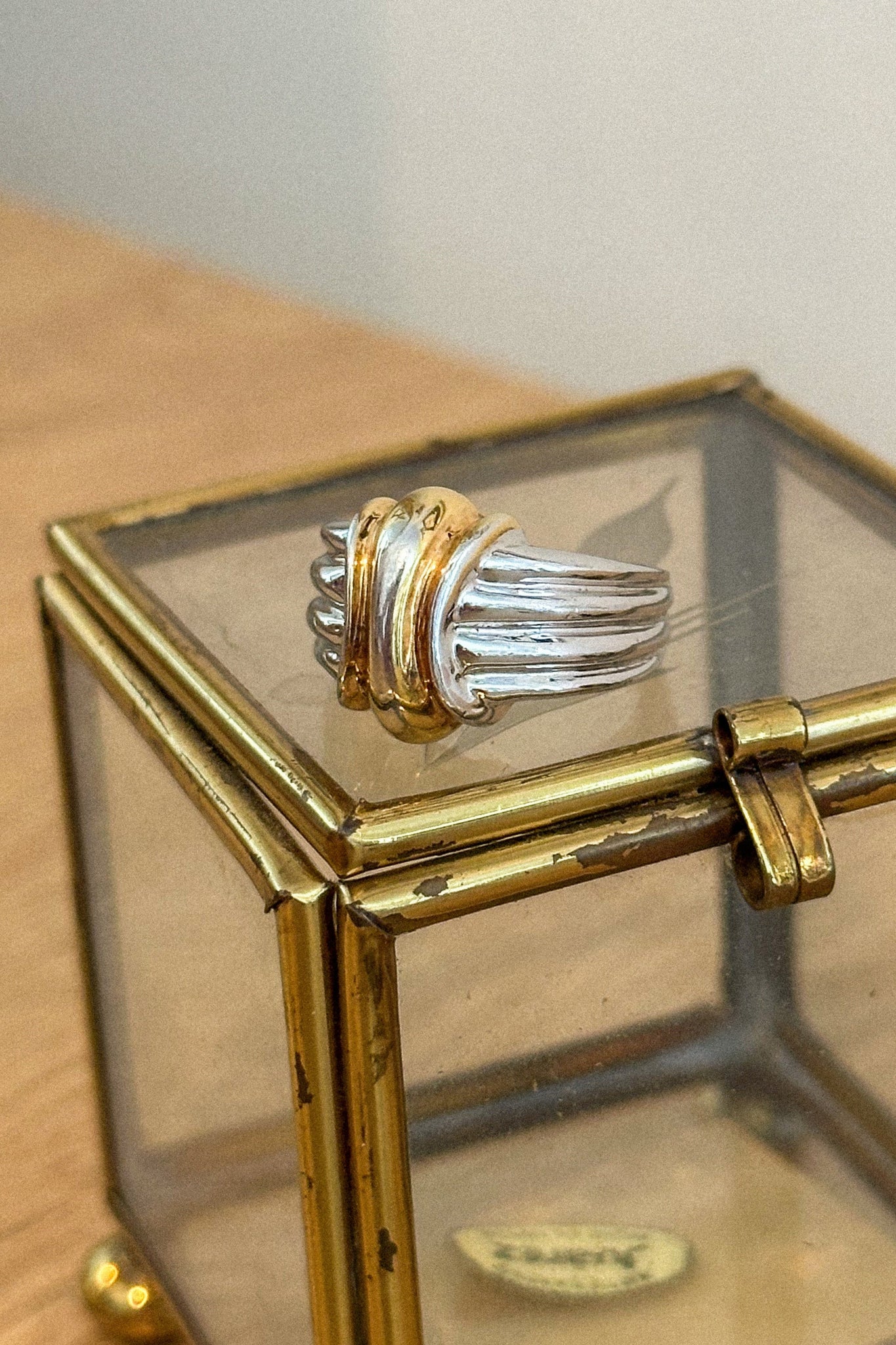 Gold and silver ring on a glass display box with a gold base.