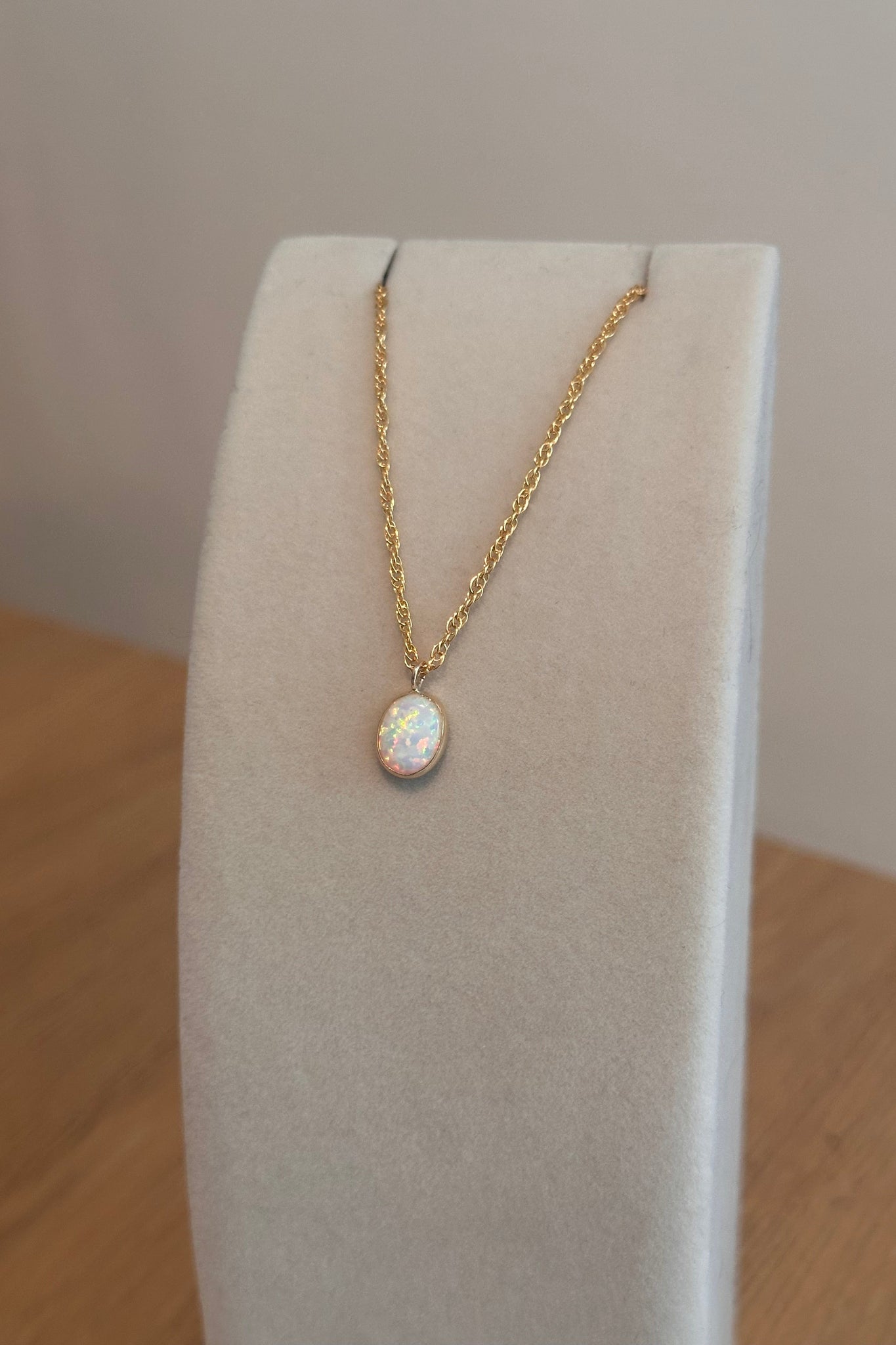 Gold necklace with a pendant on a white cushion