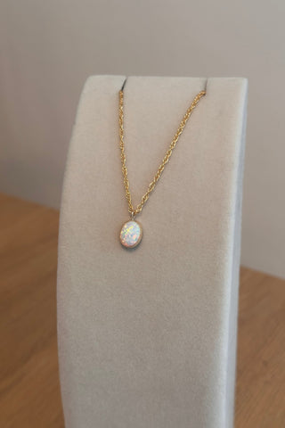 Gold necklace with a pendant on a white cushion