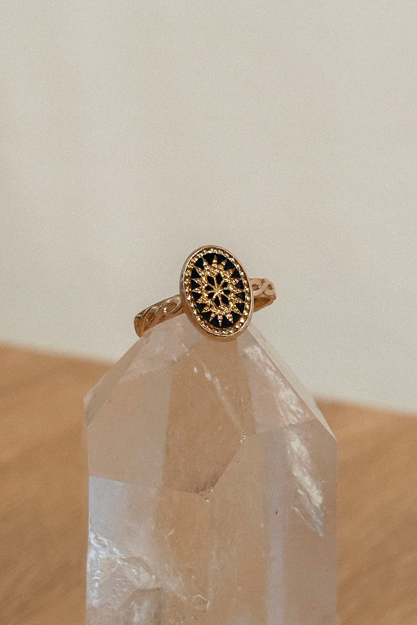 Gold ring with black gemstone on a clear crystal on a wooden surface