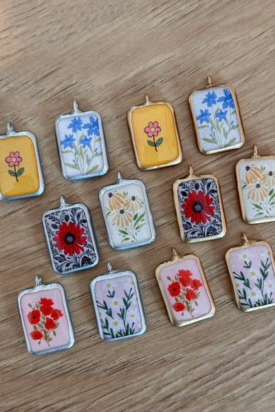 Small rectangular pendants with floral designs on a wooden surface