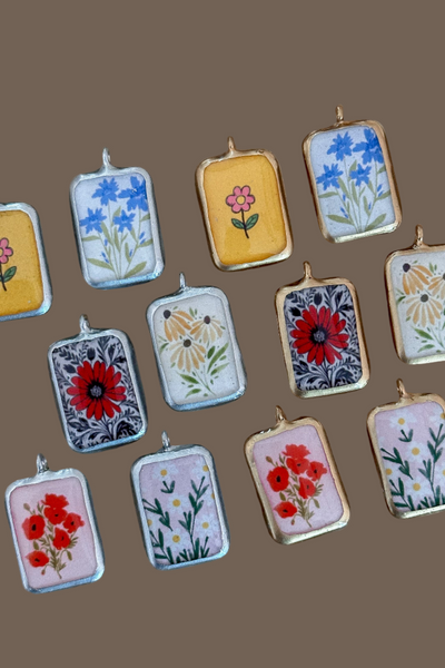 Small rectangular pendants with floral designs on a wooden surface