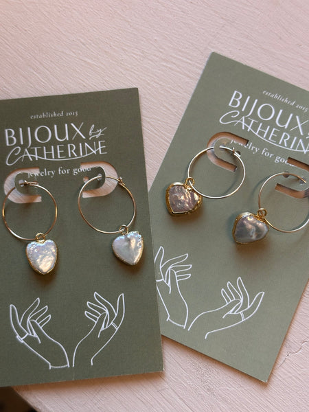 Pair of gold hoop earrings with heart-shaped stones on a green card with 'Bijoux Catherine' branding.