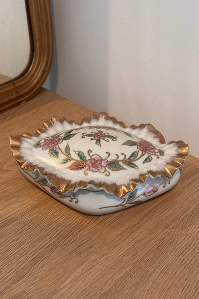 Decorative ceramic trinket box with floral patterns on a wooden surface.