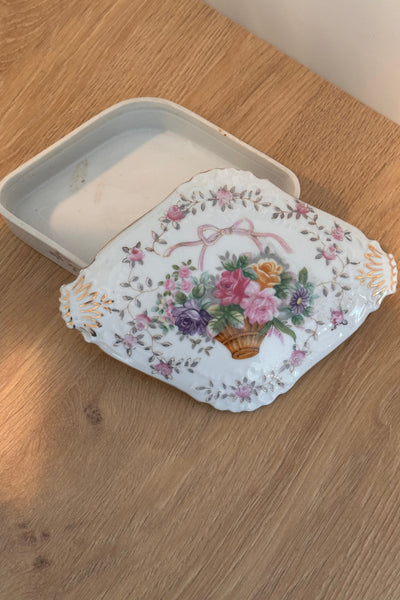 Decorative floral-patterned lid on a white container on a wooden surface