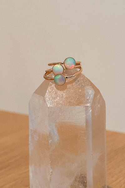 Two gold rings with opal stones on a clear crystal prism