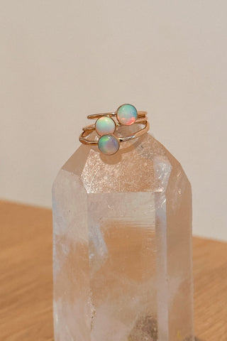 Two gold rings with opal stones on a clear crystal prism